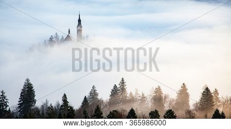 amazing panorama of Lake Bled Blejsko Jezero on a foggy morning with the Pilgrimage Church of the Assumption of Maria on a small island and Bled Castle and Julian Alps in backgroud