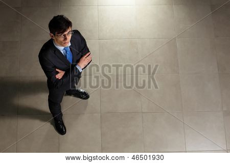 Image of young businessman in glasses arms crossed. Top view