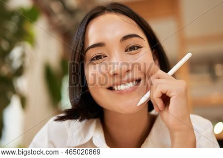 Close Up Portrait Of Smiling Brunette Asian Woman, Sitting With Graphic Pen And Looking Happy, Drawi