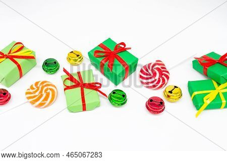 Happy Holidays: Gifts With Lollipops And Red, Green, Golden Bells On A White Background, Copy Space.