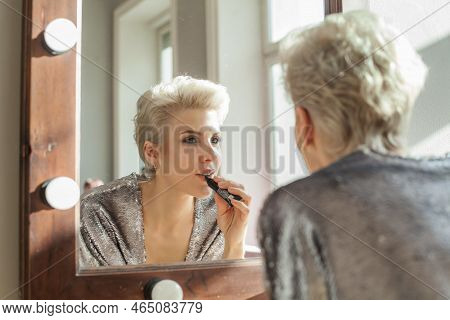 Beautiful Blonde Short Haired Woman Is Applying Lipsick Make Up And Looking To The Mirror