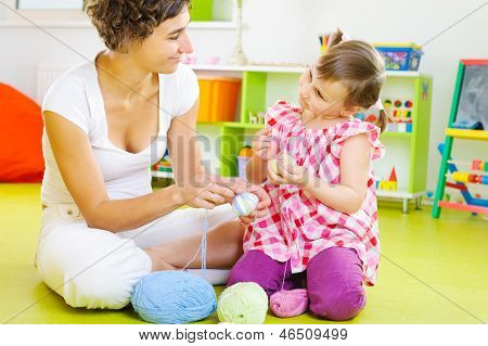 Joven madre e hija pequeña decoración de huevos de Pascua