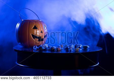 A Plastic Pumpkin Jack O Lanter Bucket For Trick Or Treating With Saltwater Taffy On A Table Against