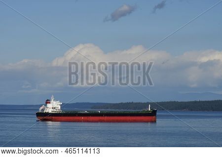 An Image Of A Large Red And Black Cargo Ship Heading Out To The Pacific Ocean.