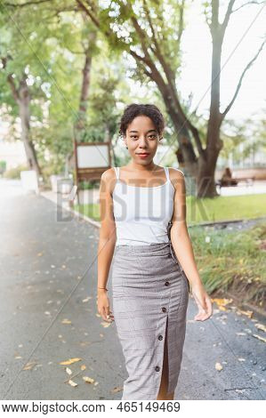 Young African American Multiracial Woman In Midi Pencil Skirt With Front Button Slit In Park Or Stre
