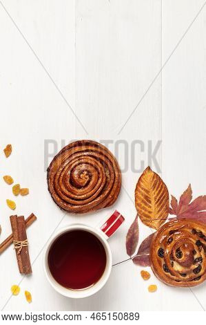Light Wooden Background With A Cup, Sweet Buns And Autumn Leaves.