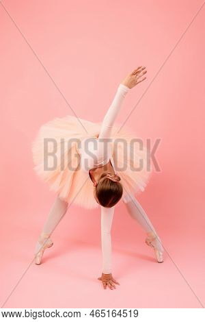 Flexible Young Ballerina Standing On Toes And Touching Floor With One Hand While Another Outstretche