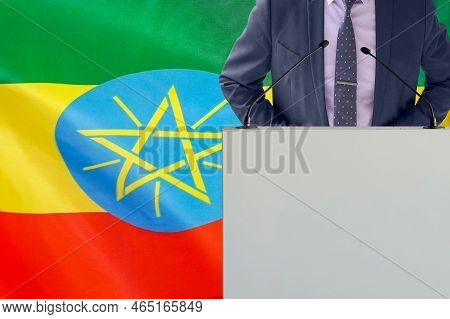 Tribune With Microphone And Man In Suit On Ethiopia Flag Background. Businessman And Tribune On Ethi