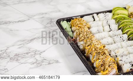 Pre-packaged Variety Of Sushi And Sushi Rolls In A Plastic Tray.