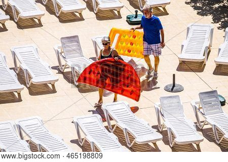 People In Summer Time With Adult Senior Caucasian Coiple With Coloured Trendy Lilos Approaching To T