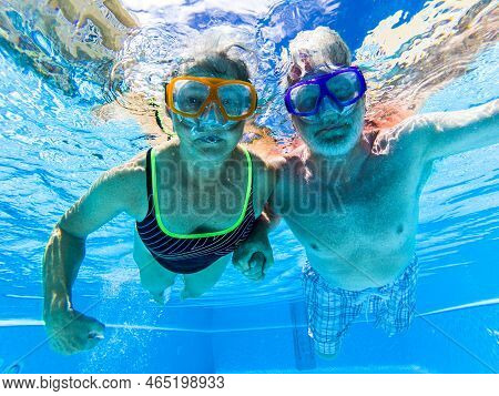 Adult People Senior Couple Have Fun Swimmin In The Pool Underwater With Coloured Funny Diving Masks 