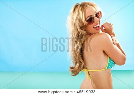 Vivace dai lunghi capelli bionda donna in bikini guardando indietro sulla sua spalla alla telecamera come lei s