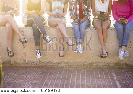 Group Of Young Women In Friendship Together Using Cellula Phone Technology In The Summer With Sun In