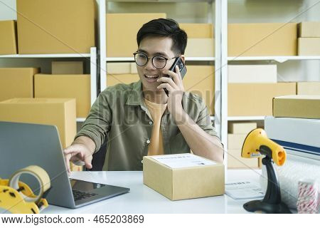 Young Male Small Business Enrtrepreneur, Online Store Owner Working On Laptop With Boxes On Desk At 