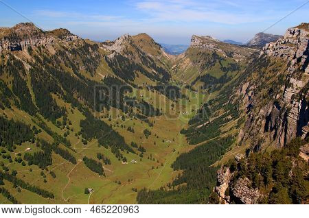 Landscape With Mountains, A Hollow And Houses In It Against A Blue Sky With Clouds On A Mountain Nie