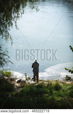 Undefined Man Is Fishing In The Dniester River. Dirty Film Of Sewage Near The Banks Of The Dniester 