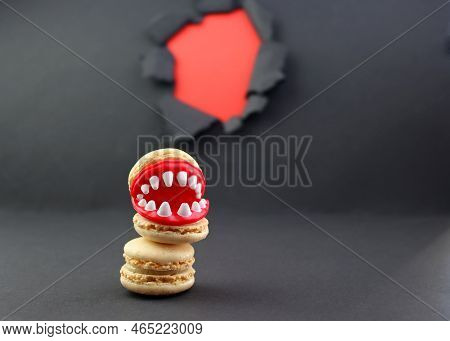 Plastic Teeth Lying Between Macaroon Halves.  A Frightened Beige Macaroon On A Gray Background With 