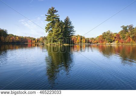 Pretty Blue Lake With Trees In Autumn Color And A Small Island On A Bright Morning