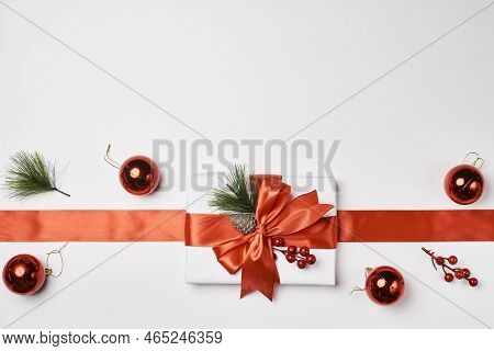 Christmas Decorations On A White Background With An Orange Ribbon And Red Baknots Tied Around The Gi