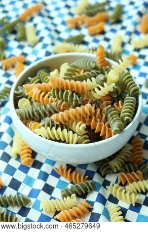 Organic Fusilli Tricolore Spilling On Pink Background