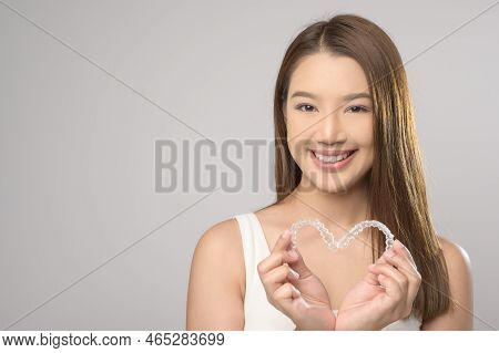 Young Smiling Woman Holding Invisalign Braces Over White Background Studio, Dental Healthcare And Or