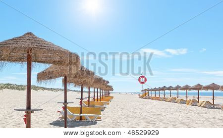 Kauniin aurinkoisen Portugalissa on aurinkovarjoja ja aurinkotuoleja rannalla. Kesä.