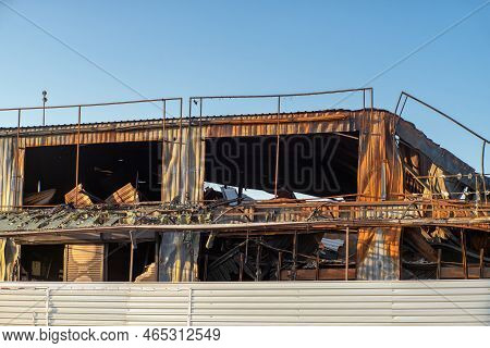 Industrial Building After Fire With Broken Roof, Walls And Piles Of Garbage.