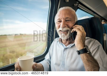Close-up Of Smiling Elderly Professional Talking On Mobile Phone. Senior Businessman Is Having Coffe