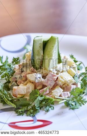 A Salad On A White Plate With Cus And Avocal Garni In The Background Is A Wooden Table