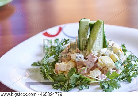 A Salad On A White Plate With Cus And Ceints In The Center, Sitting On A Wooden Table