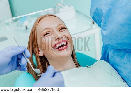 Attractive Young Woman Smilling With Natural White Teeth In Dental Clinic. Hands Doctor Dentist With