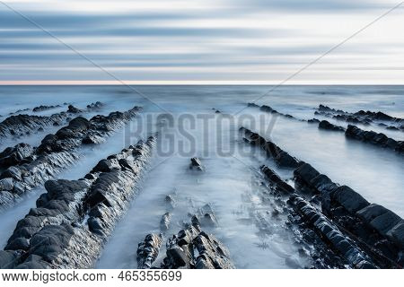 Stunning Sunset Landscape Image Of Welcome Mouth Beach In Devon England With Beautiful Rock Formatio
