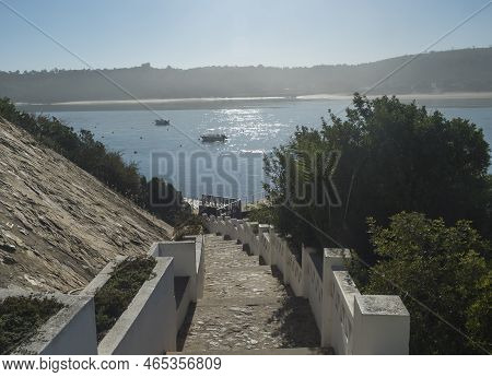 View Of Stairs Leading To Pier With Small Ferry Boat Across The River Mira Flowing Into The Atlantic