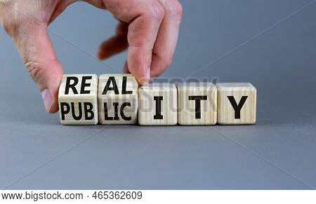 Reality Or Publicity Symbol. Businessman Turns Wooden Cubes And Changes The Word Publicity To Realit