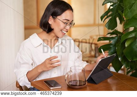 Young Artist Drawing On Digital Tablet, Using Graphic Pen, Drinking Coffee In Cafe And Scatching Smt