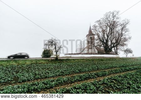 Rural Country With Blurred Car Motion And Old Gothic Church In Ludrova Village In Slovakia.