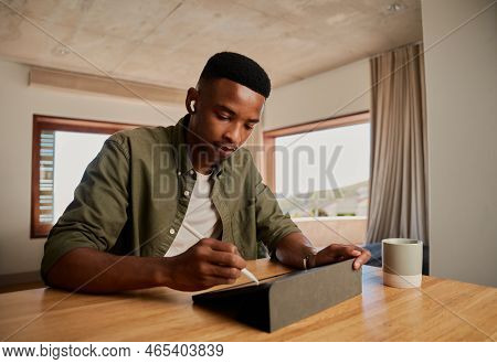 Focussed Young Adult Black African American Male Writing With Pen On Electronic Tablet While Working
