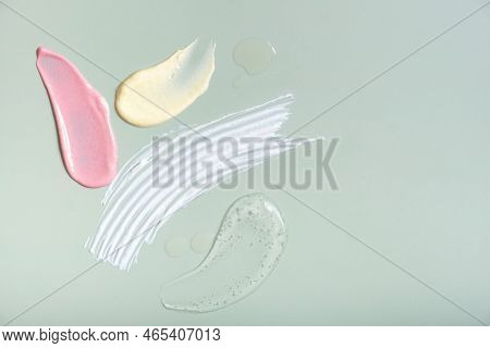 Colored Cosmetic Smears On Pastel Green Background Top View. Self Care Concept.