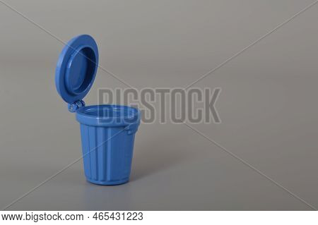 Blue Trash Can Isolated On A Grey Background. Copy Space For The Text.