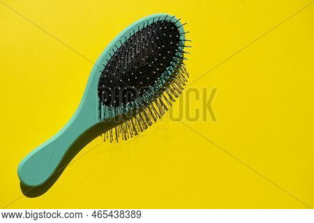 Green Comb And Fallen Hair On The Yellow Background. Baldness And Hair Loss Problem