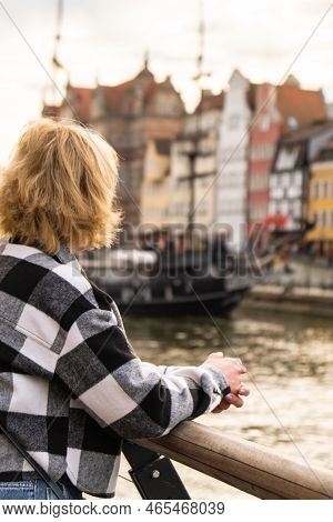 Unrecognizable Tourist Traveler In Old Town In Gdansk. Woman Looking On Riverside On Granary Island 
