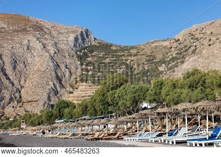 Kamari, Santorini, Greece - July 3, 2021: Sun Loungers On The Black Volcanic Beach Of Kamari In Sant