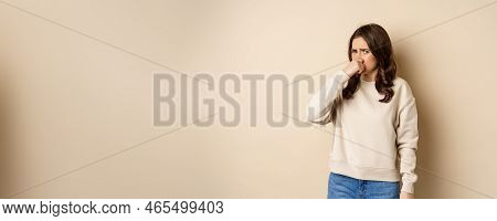 Woman Expressing Disgust Of Bad Disgusting Smell, Close Nose And Grimaing From Dislike, Standing Ove