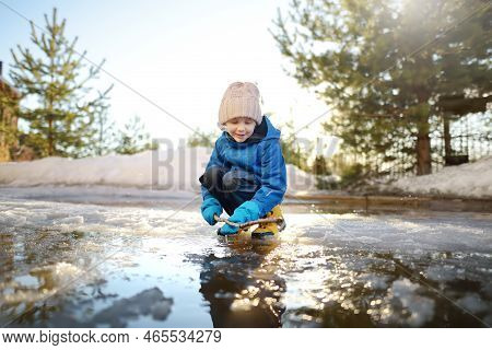 Preschooler Boy Is Playing With A Stick In Brook On Sunny Day. Child Having Fun And Enjoy A Big Pudd