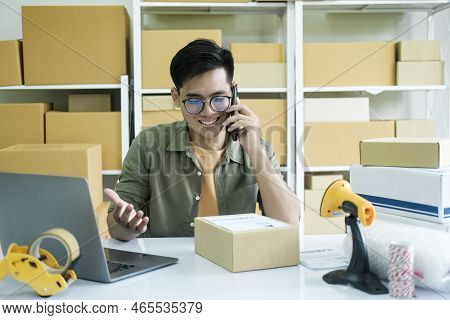 Young Male Small Business Enrtrepreneur, Online Store Owner Working On Laptop With Boxes On Desk At 