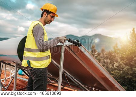 Man Works On Renewable Energy System With Solar Panel For Hot Water