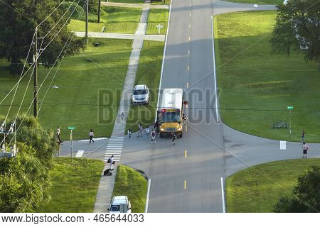 Top View Of Standard American Yellow School Bus Picking Up Kids At Rural Town Street Stop For Their 