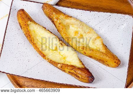 Top View Of Baked Ripe Plantains With Cheese (plantain Canoe Or Platanos Asados Con Queso) On A Plat
