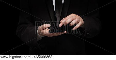 Business Person In Black Siut Hand With Mobile Phone Against Black Background
