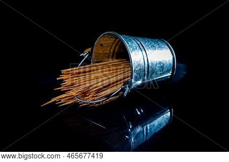 Bamboo Wooden Toothpicks In Glass Jar, Wine Glass. In Bucket. Toothpicks On Black Background. Front